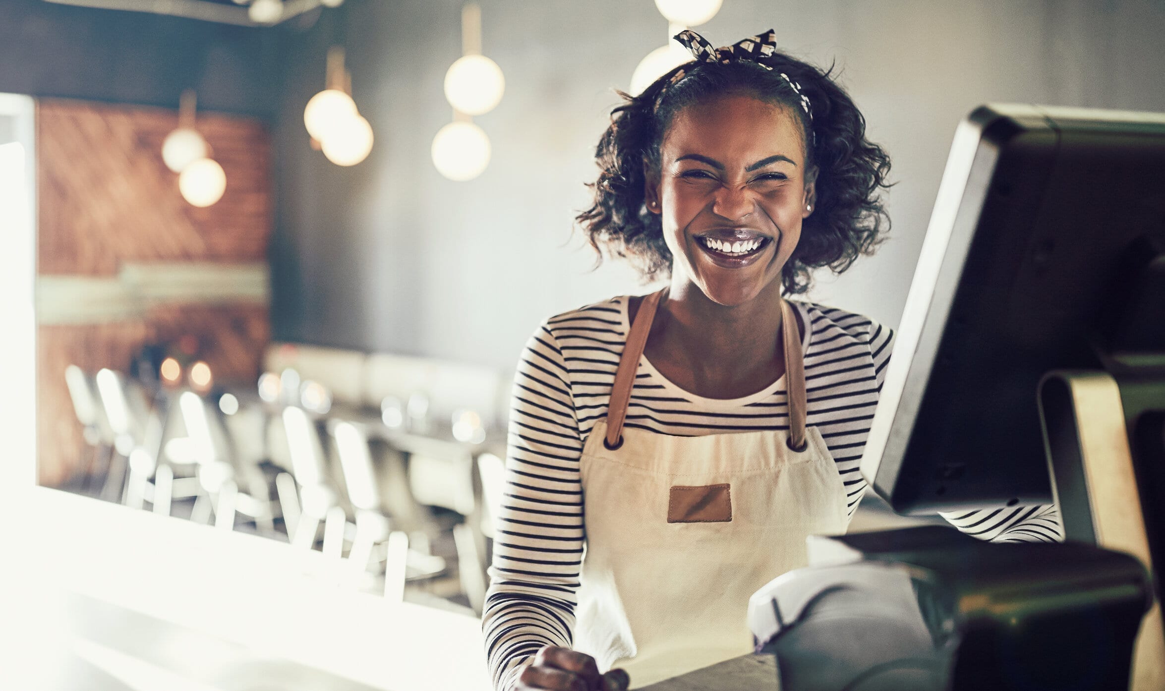 Laughing young African waitress working in a trendy restaurant